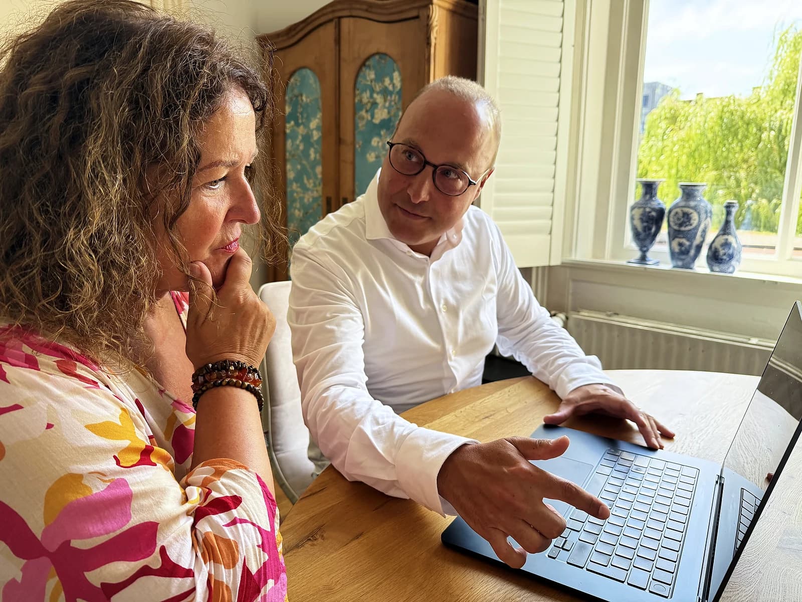Een cliënt en haar audicien overleggen samen achter een laptop